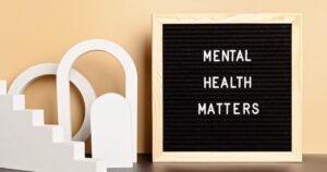 Letter board reads 'MENTAL HEALTH MATTERS' next to white abstract arches against a beige background.