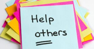 Blue sticky note with the words 'Help others' surrounded by colorful sticky notes.