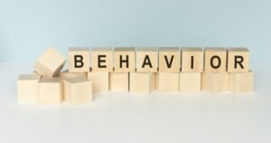 - Treat Mental Health California Wooden blocks arranged to spell BEHAVIOR on a light blue backdrop.