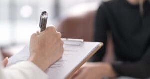 - Treat Mental Health California Close-up of a hand writing on a clipboard with a pen during a meeting or interview setting.