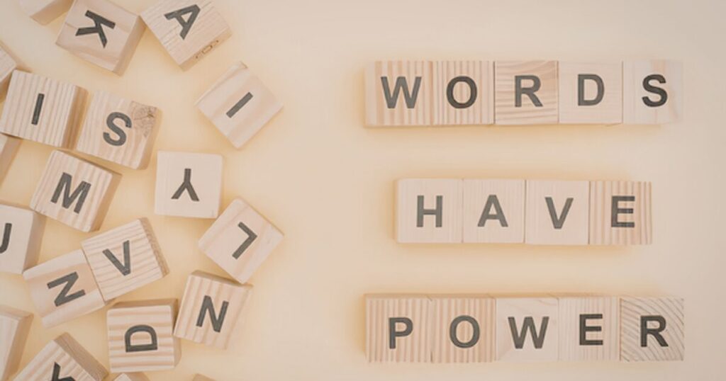 Wooden letter tiles spell 'WORDS HAVE POWER' on a beige background with scattered letters to the left.