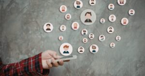 Hand holding a smartphone with interconnected circular avatars representing an online social network of people.