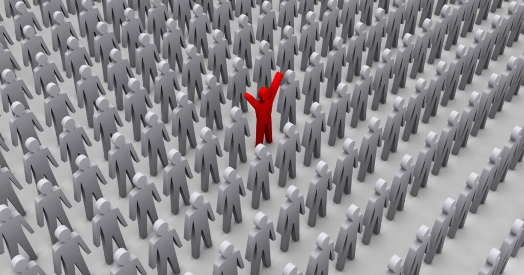 Red figure stands out in a gray crowd with arms raised, symbolizing leadership or uniqueness.