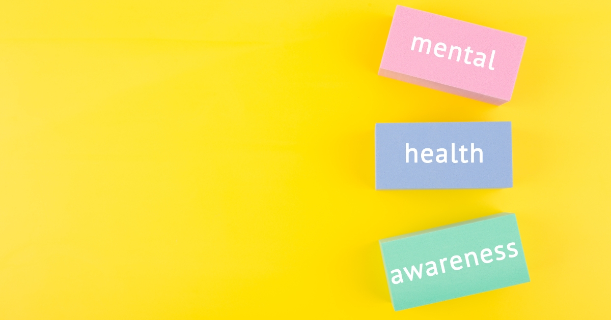 Pastel blocks spell out 'mental', 'health', 'awareness' on a bright yellow background, signaling mental health awareness.